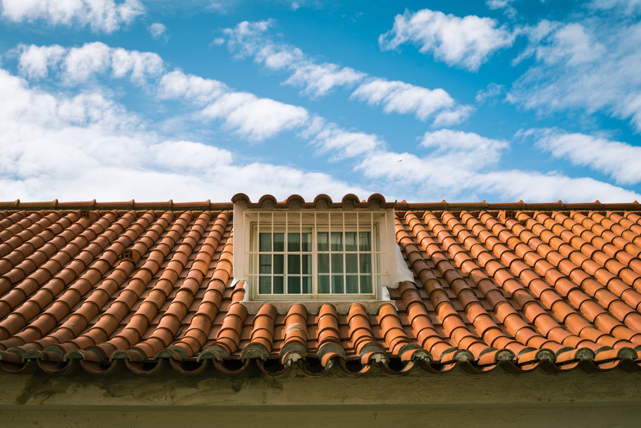 about-01 Close-up of a terracotta tiled roof with a skylight window in sunny Marbella, Spain.