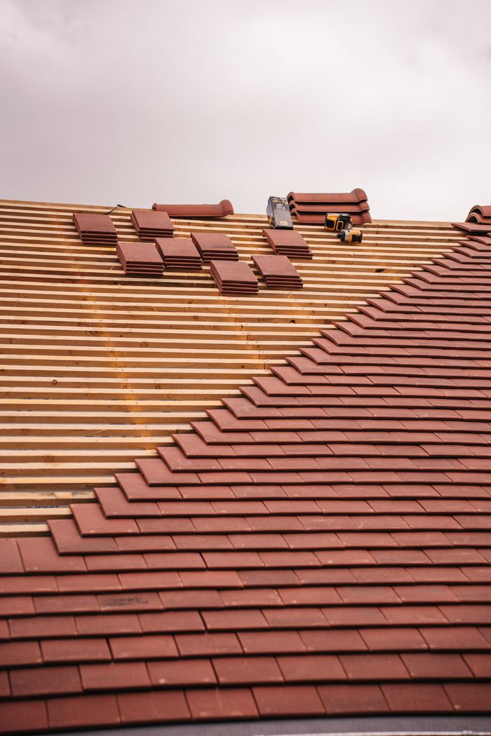 services-02 Partial installation of a terracotta tile roof on a building in progress.