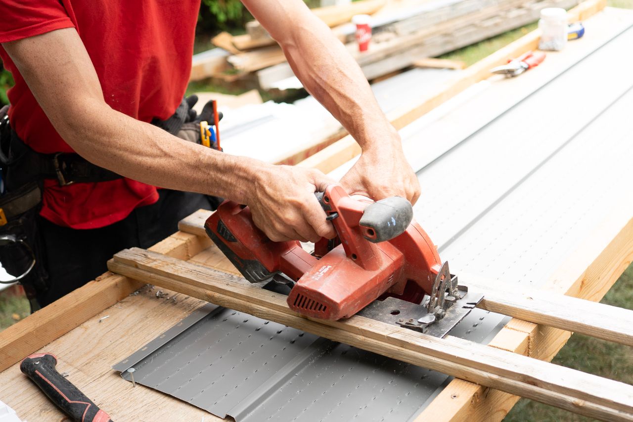 gallery-4 Carpenter cutting wood with a circular saw at an outdoor construction site, showcasing craftsmanship.